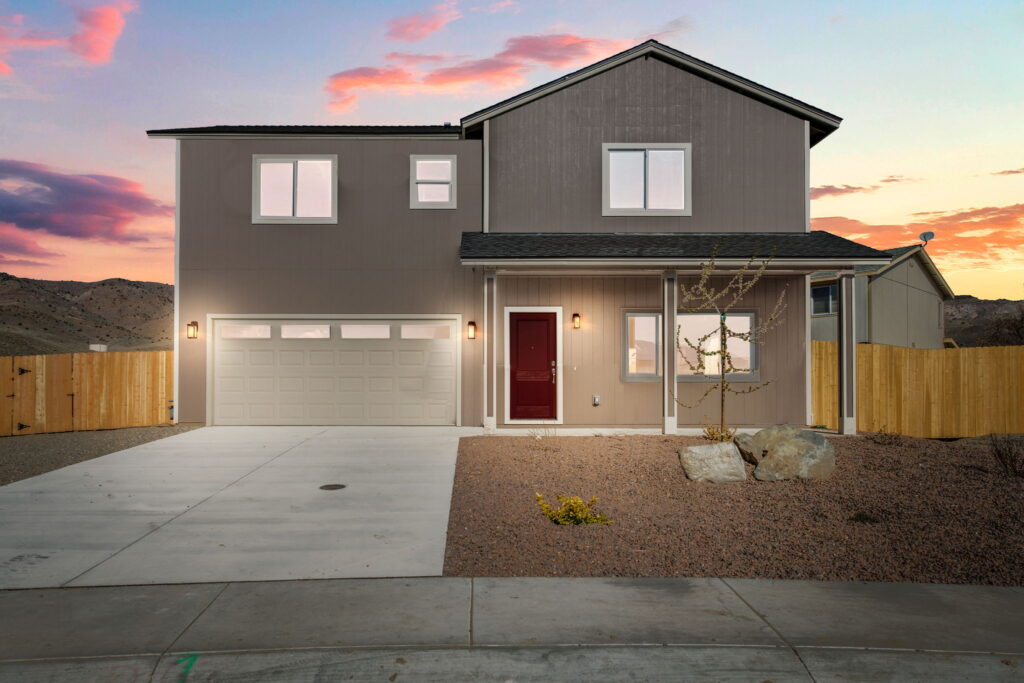 Newly constructed two-story home in Dayton Gold Country Estates Phase 4, illuminated at sunset with a two-car garage and modern design.